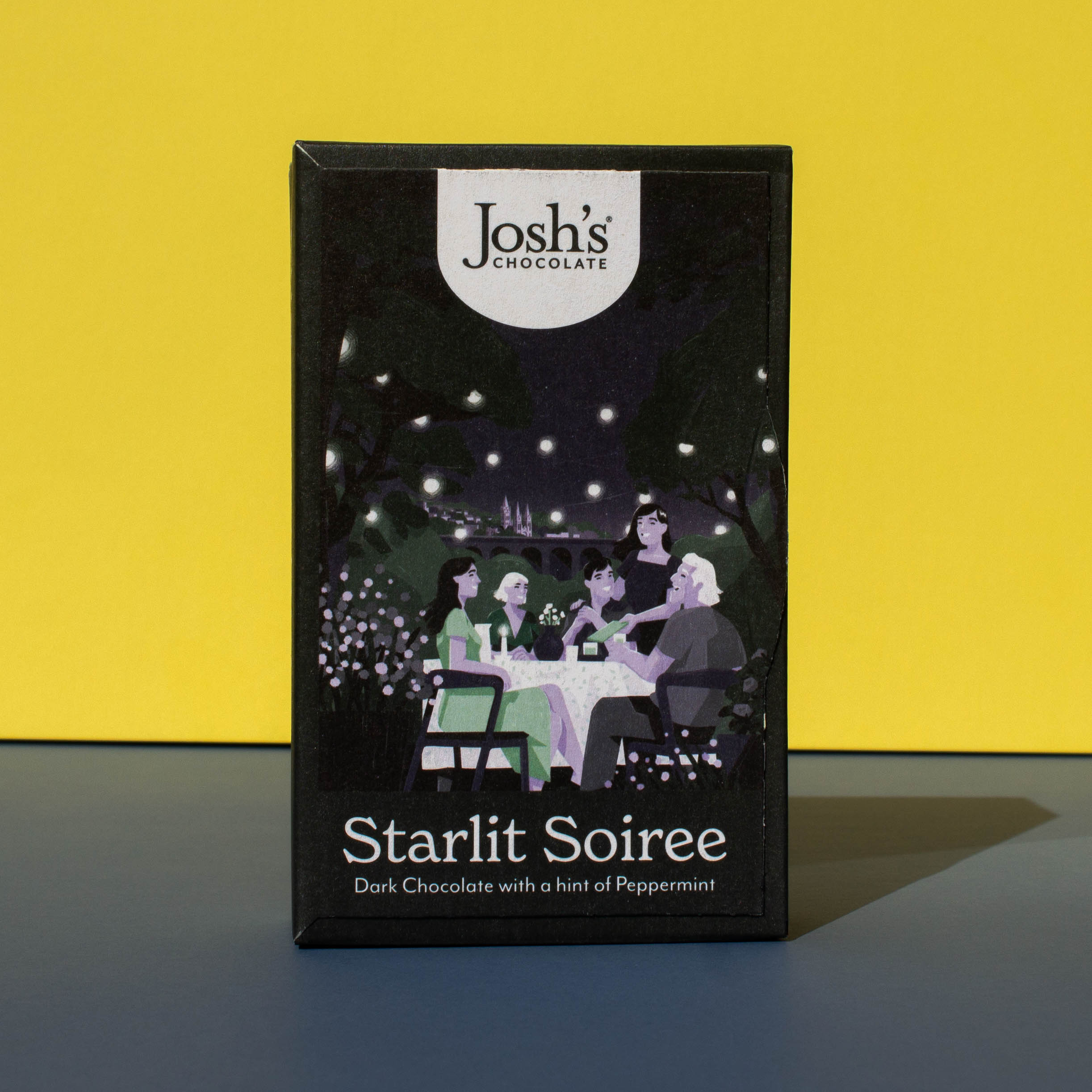 Box of Josh's Dark Chocolate Peppermint Buttons, it is a black box an with illustration of a late night gathering of friends, it is placed on a blue and yellow background.