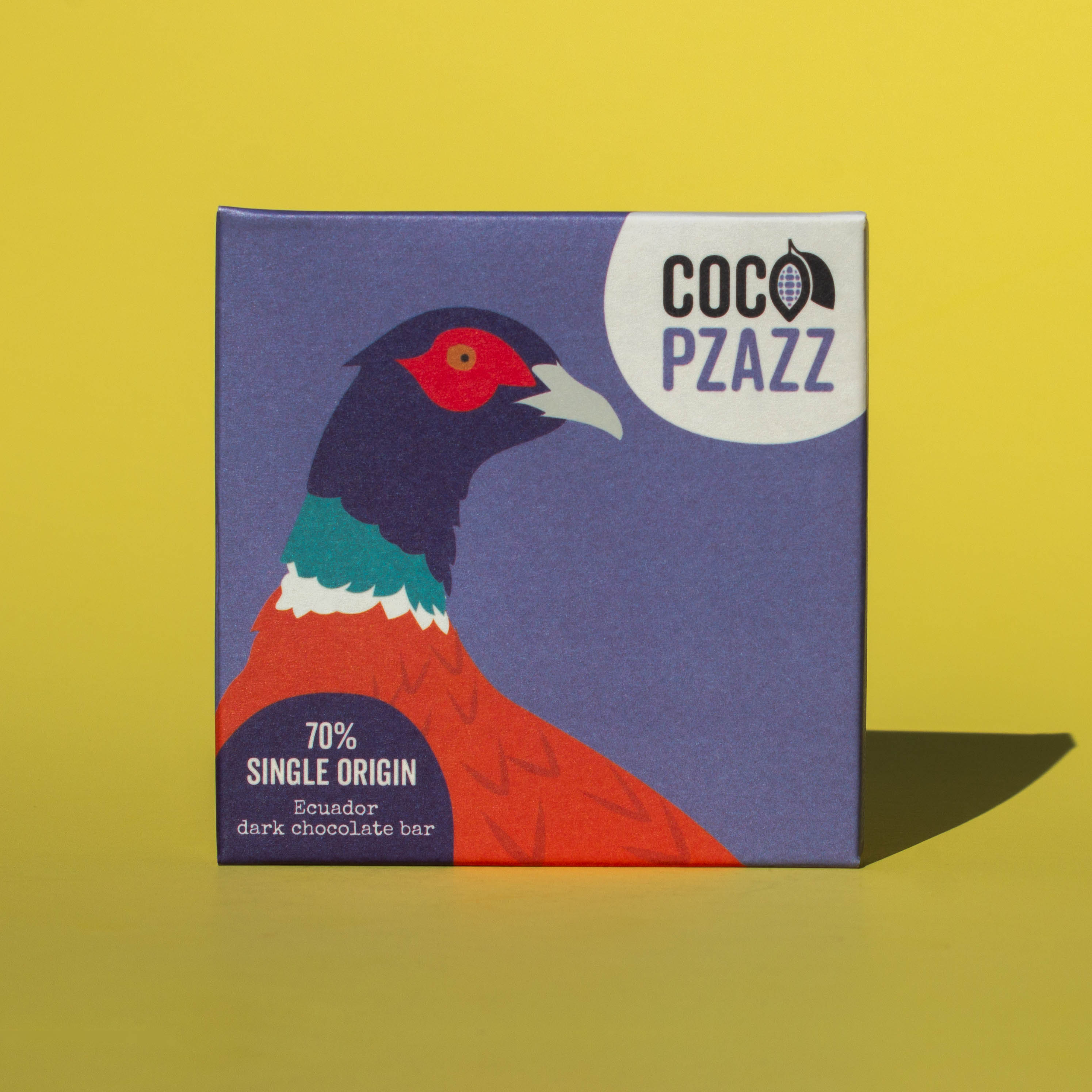Bar of Coco Pzazz Ecuador Dark Chocolate, it has a blue wrapper with an illustration of a pheasant, it is placed on a yellow background.
