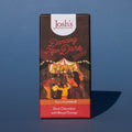 Bar of Josh's Dark Chocolate with Blood Orange, it is a dark orange and red paper wrapper with an illustration of an outdoor music event, it is placed on a blue background.